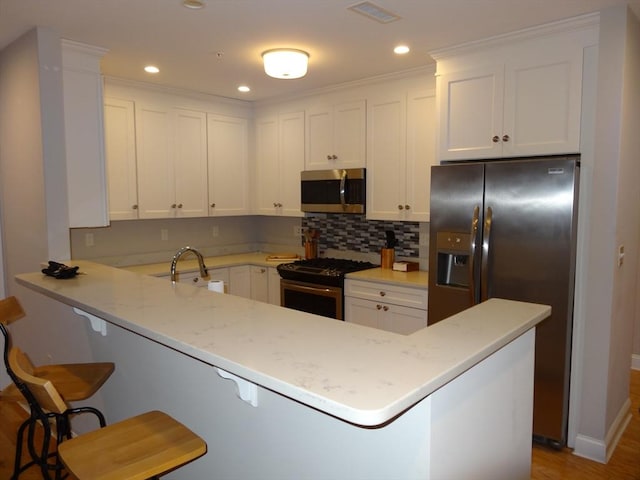 kitchen featuring a kitchen breakfast bar, sink, light stone countertops, appliances with stainless steel finishes, and kitchen peninsula