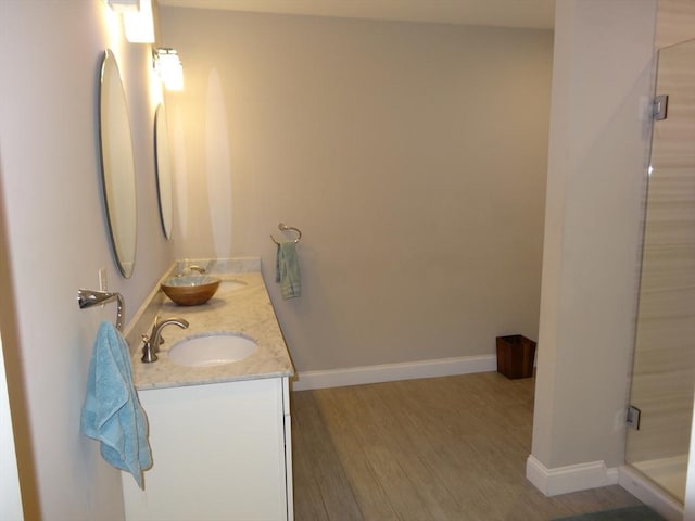 bathroom with hardwood / wood-style flooring, vanity, and a shower with shower door