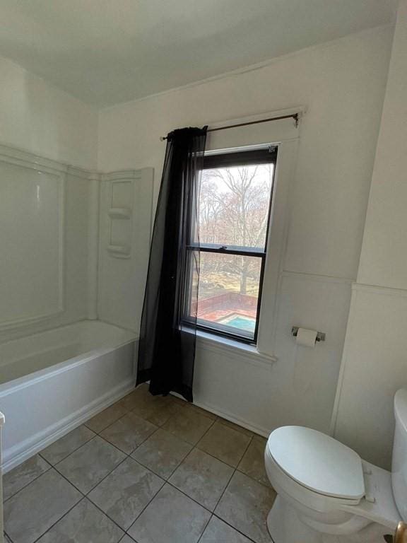 bathroom with tile patterned flooring, shower / washtub combination, and toilet