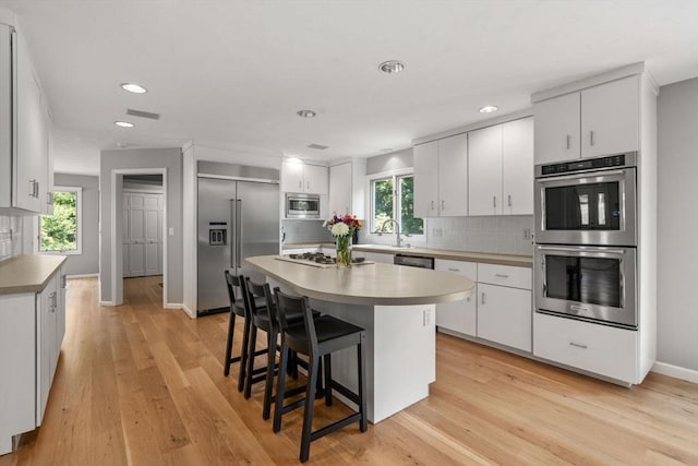 66 Ashcroft Rd, Sharon, MA 02067 - kitchen featuring built in appliances, decorative backsplash, a breakfast bar area, light wood-style floors, and recessed lighting