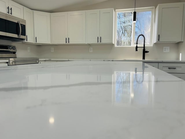 kitchen featuring white cabinets, pendant lighting, range with electric stovetop, and sink