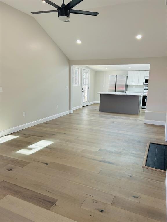 unfurnished living room featuring ceiling fan, vaulted ceiling, and light wood-type flooring