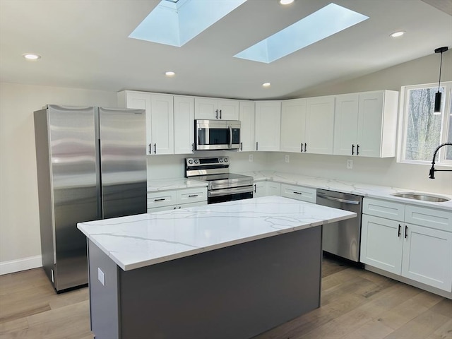 kitchen featuring sink, light hardwood / wood-style flooring, lofted ceiling with skylight, a kitchen island, and appliances with stainless steel finishes