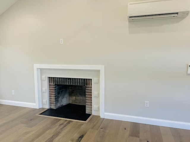 details featuring an AC wall unit, hardwood / wood-style floors, and a brick fireplace