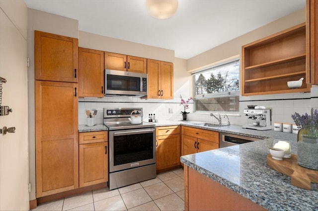 kitchen featuring decorative backsplash, light tile patterned floors, appliances with stainless steel finishes, and a sink