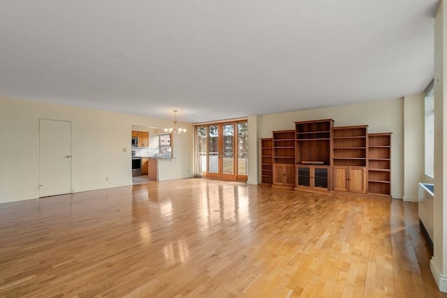 unfurnished living room with a notable chandelier and light wood-style floors