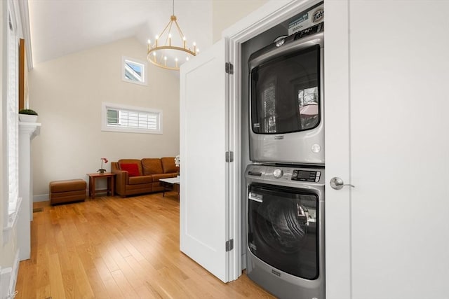 laundry area featuring stacked washer and dryer, laundry area, a notable chandelier, and light wood finished floors
