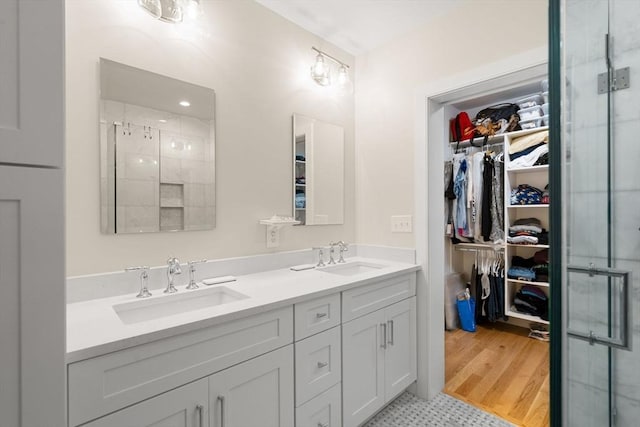 full bathroom featuring a spacious closet, a shower stall, and a sink