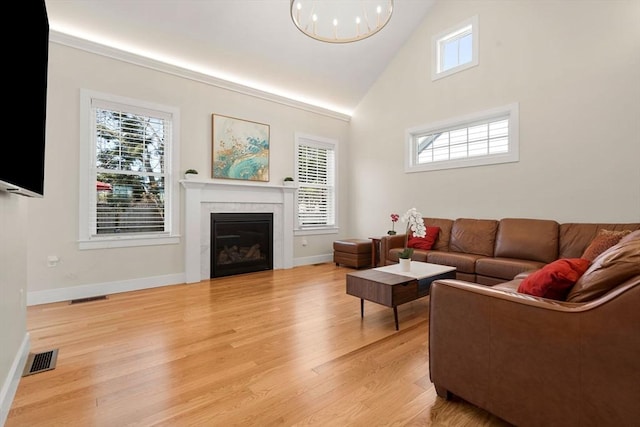living area featuring high vaulted ceiling, visible vents, light wood-style floors, and a tile fireplace