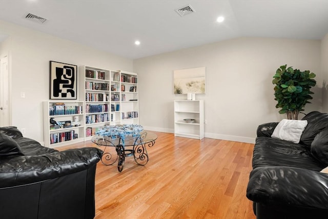 living room featuring visible vents, baseboards, wood finished floors, and vaulted ceiling