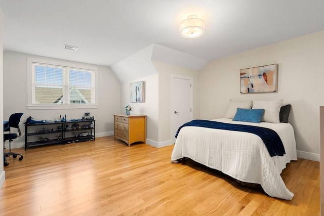 bedroom featuring baseboards, visible vents, lofted ceiling, and light wood-type flooring