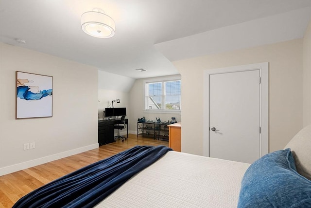 bedroom with baseboards, lofted ceiling, and wood finished floors