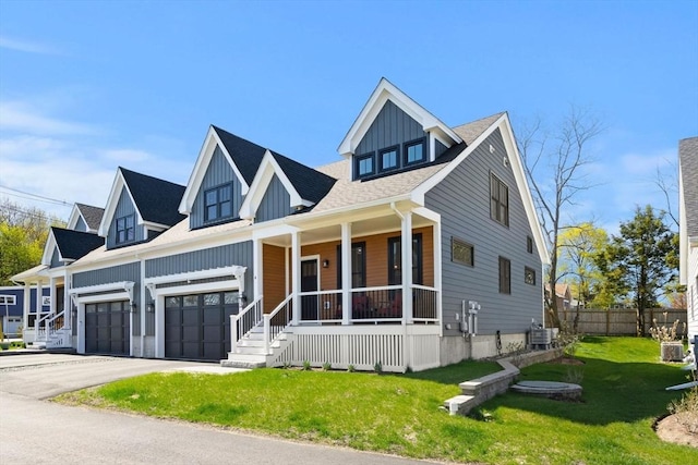 view of front facade featuring fence, a porch, a front yard, cooling unit, and driveway
