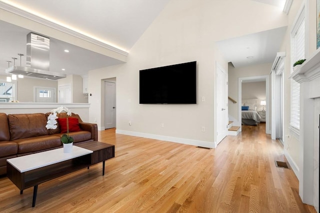 living room featuring visible vents, a fireplace, high vaulted ceiling, stairway, and light wood-style flooring