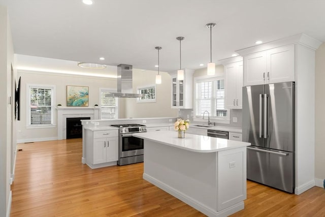 kitchen featuring island exhaust hood, a sink, light countertops, a peninsula, and stainless steel appliances