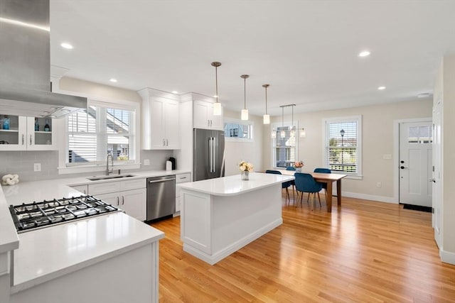 kitchen featuring appliances with stainless steel finishes, light wood-type flooring, a sink, light countertops, and white cabinetry