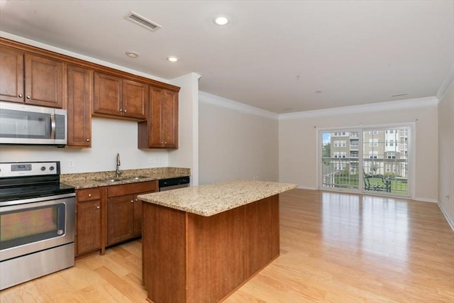 1 Francis Dr Unit 211, Andover, MA 01810 - kitchen featuring appliances with stainless steel finishes, a sink, ornamental molding, light wood-style flooring, and a kitchen island