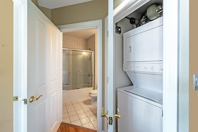 laundry room featuring stacked washer and clothes dryer and light tile patterned flooring