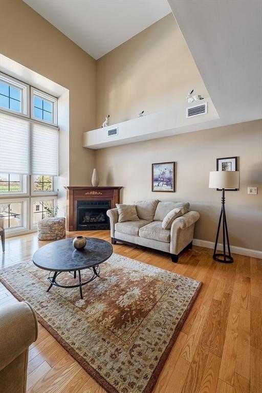 living room with light hardwood / wood-style floors and a towering ceiling