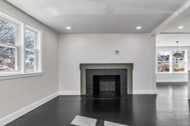 unfurnished living room featuring a fireplace with flush hearth, baseboards, and wood finished floors