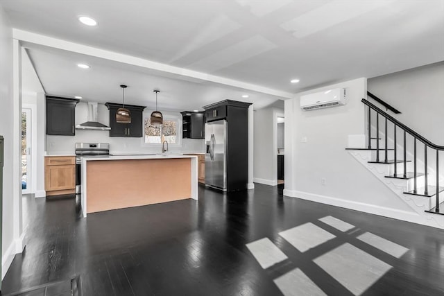 kitchen with a wall mounted air conditioner, appliances with stainless steel finishes, wall chimney exhaust hood, light countertops, and dark wood-style flooring