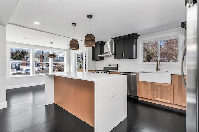 kitchen featuring a sink, appliances with stainless steel finishes, wall chimney exhaust hood, light countertops, and dark wood-style flooring