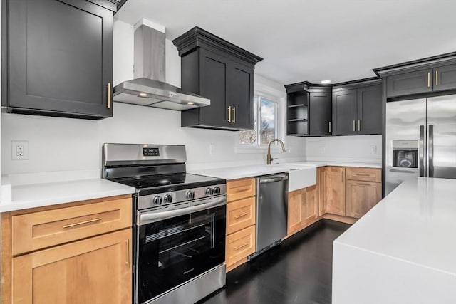 kitchen with light countertops, wall chimney exhaust hood, appliances with stainless steel finishes, and a sink