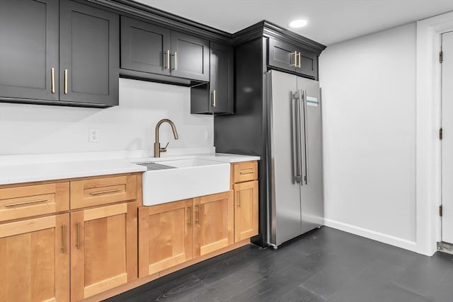 kitchen with baseboards, a sink, light countertops, dark wood-type flooring, and high end refrigerator