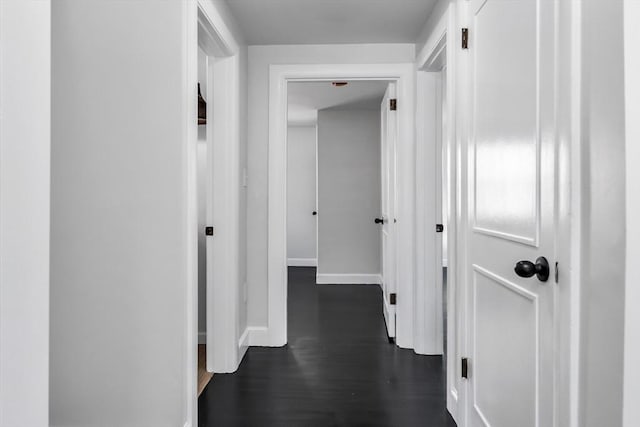 corridor featuring dark wood finished floors and baseboards