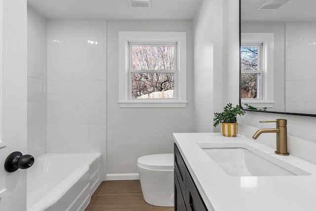 full bath with vanity, wood finished floors, visible vents, baseboards, and toilet