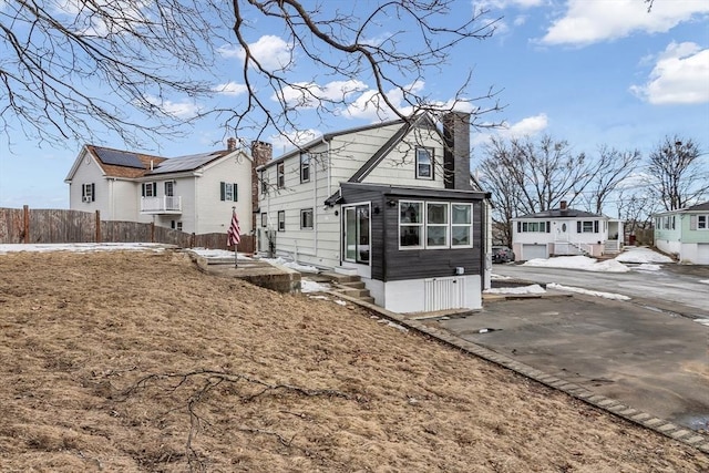 view of front of house featuring a residential view, a chimney, and fence