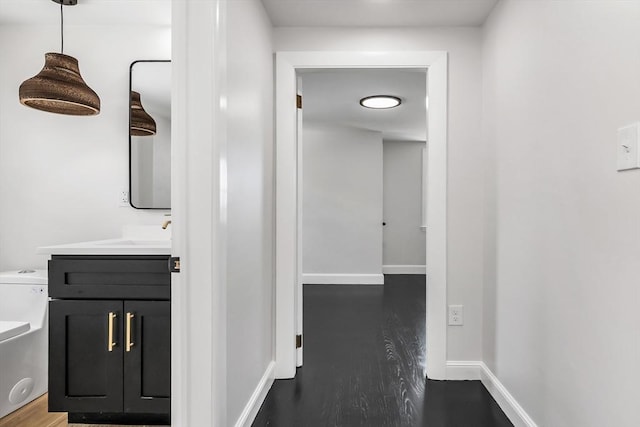 hallway with a sink, baseboards, and wood finished floors