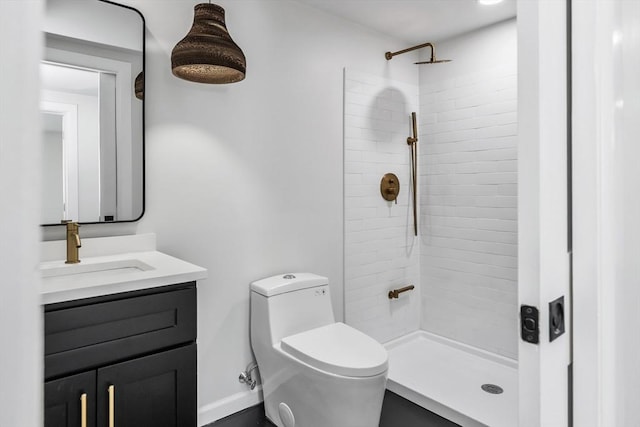 full bathroom with toilet, tiled shower, and vanity