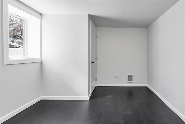 unfurnished room featuring visible vents, baseboards, and dark wood-style flooring