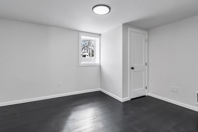 unfurnished room featuring visible vents, dark wood-type flooring, and baseboards