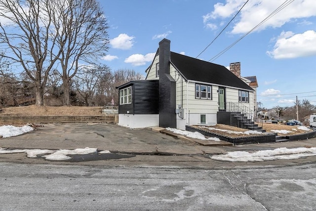 view of side of property featuring aphalt driveway and a chimney