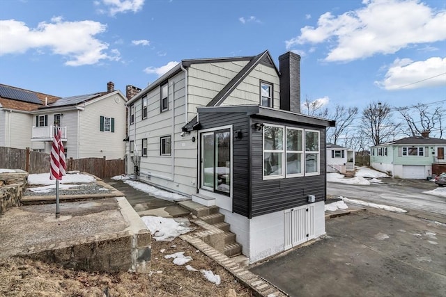 back of property featuring fence, a residential view, entry steps, a chimney, and a patio