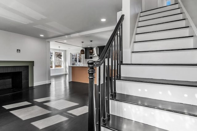 stairs featuring wood finished floors, a brick fireplace, recessed lighting, and baseboards