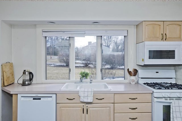 kitchen with a sink, white appliances, light brown cabinets, and light countertops