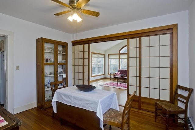 interior space with a ceiling fan, lofted ceiling, wood finished floors, and baseboards