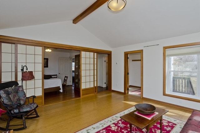 living area featuring lofted ceiling with beams, baseboards, and wood finished floors