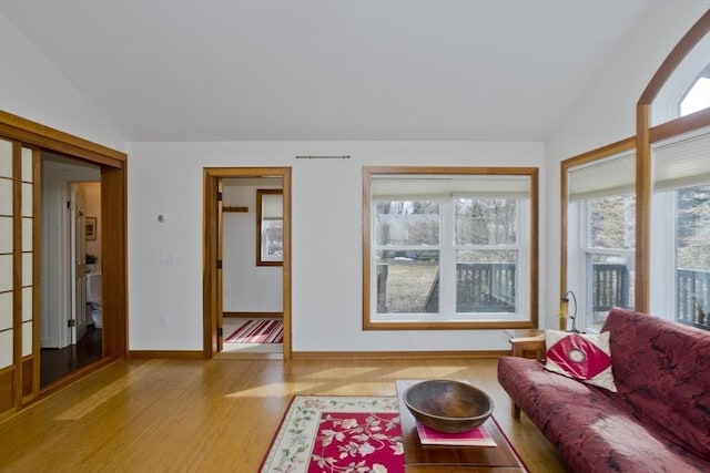 living room with baseboards, wood finished floors, and vaulted ceiling