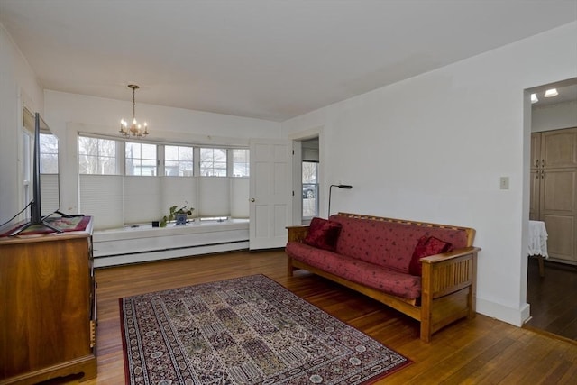 living area featuring plenty of natural light, baseboard heating, an inviting chandelier, and hardwood / wood-style floors