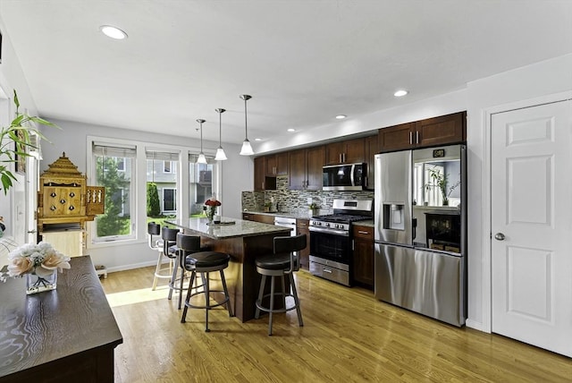 15 Queen Isabella Way Unit 15, Ashland, MA 01721 - kitchen featuring appliances with stainless steel finishes, a kitchen island, light wood-style floors, a breakfast bar, and dark brown cabinetry