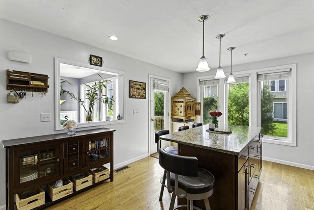 15 Queen Isabella Way Unit 15, Ashland, MA 01721 - kitchen featuring light stone counters, baseboards, light wood-type flooring, a kitchen bar, and a center island