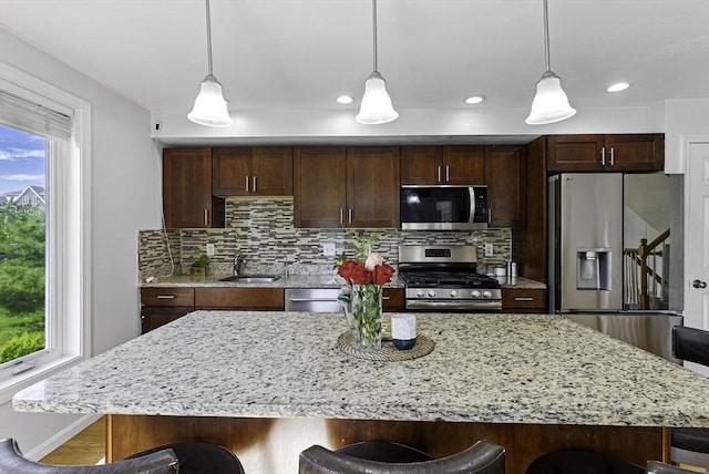 15 Queen Isabella Way Unit 15, Ashland, MA 01721 - kitchen with appliances with stainless steel finishes, a sink, a breakfast bar area, decorative backsplash, and pendant lighting