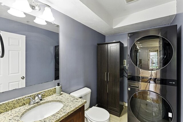 15 Queen Isabella Way Unit 15, Ashland, MA 01721 - bathroom featuring stacked washing machine and dryer, toilet, tile patterned floors, and vanity