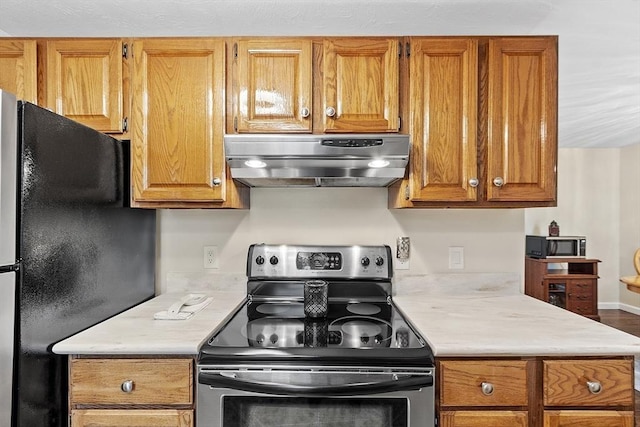 127 Bayberry Hill Ln Unit 127, Leominster, MA 01453 - kitchen with stainless steel electric range, wall chimney exhaust hood, freestanding refrigerator, light countertops, and brown cabinets
