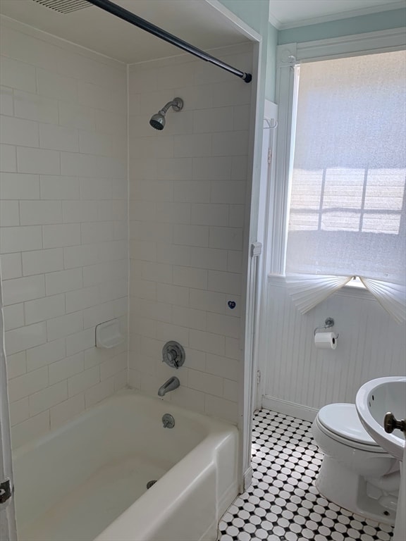 bathroom featuring tile patterned floors, toilet, and tiled shower / bath