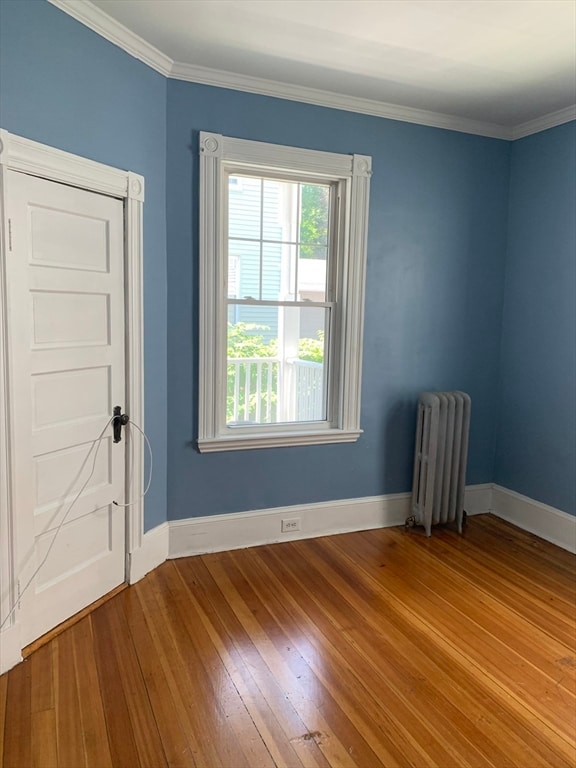 spare room featuring radiator, hardwood / wood-style floors, and ornamental molding